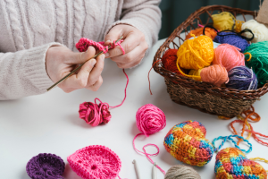 Pessoa segurando linhas e agulhas para fazer a decoração com crochê.