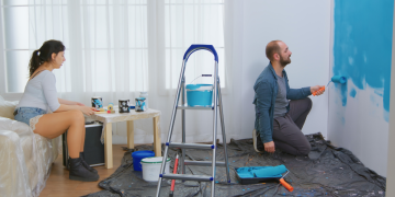 Imagem de casal ao entender como escolher as cores da casa e pintando a sala.