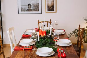 mesa posta de Natal com talheres, pratos, taças e decoração. 