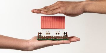 Pessoa segurando miniatura de casa, ilustrativa sobre o Minha Casa Minha Vida.