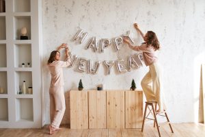 Pessoas decorando sua casa com faixa de balão ao descobrir como fazer sua festa de Ano Novo em casa 